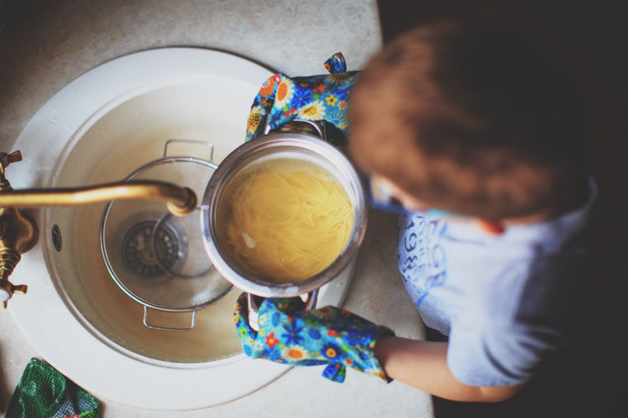 Niño cocinando pasta en cocina doméstica