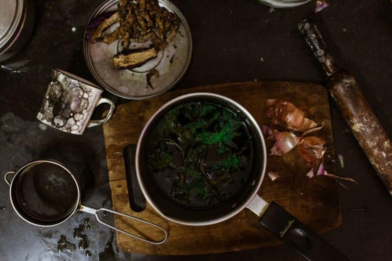 Olla metálica con verduras y utensilios de cocina